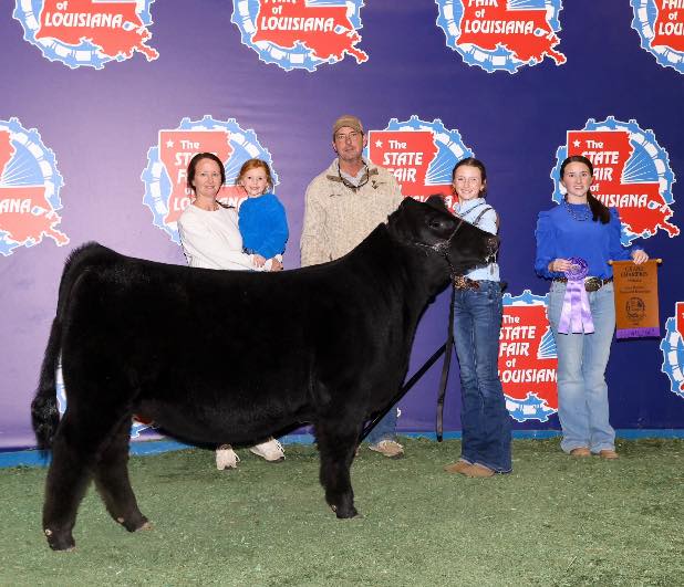 A family of five with a black cow.